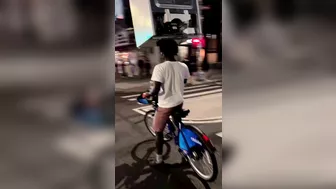 A Cyclist Carries A Refrigerator On His Head